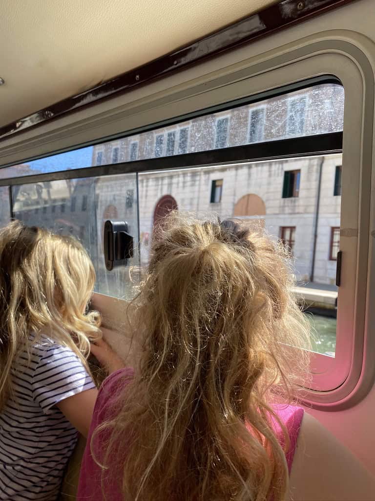 Children looking out of the window of the water bus as we arrive in Venice along the grand canal from the airport.