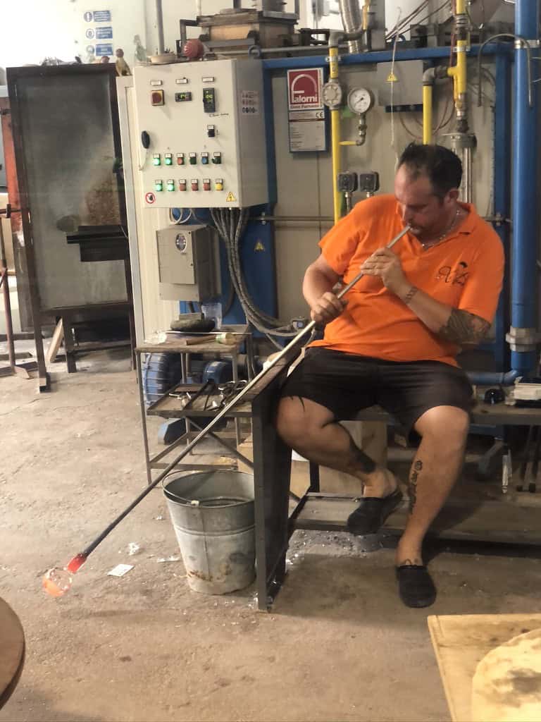 Man doing glass blowing demonstration in a glass workshop on Murano island, Venice.