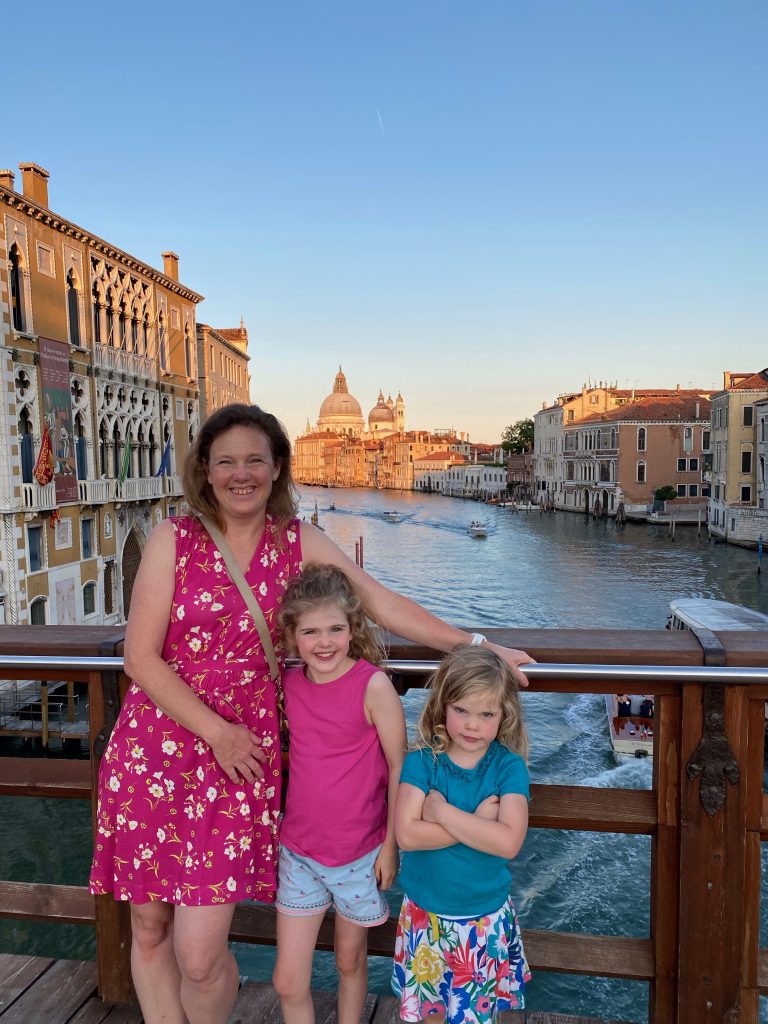Family standing on Pont dell"Accademia bridge at sunset.