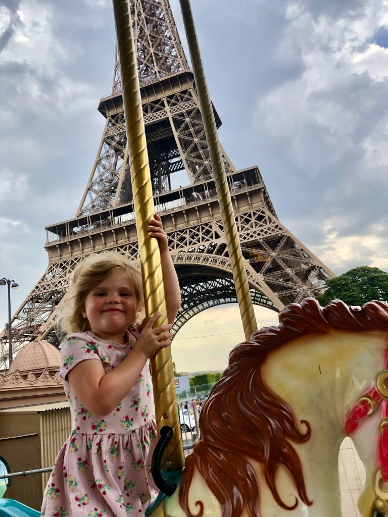 Martha enjoying a ride on the carousel with the Eiffel tower in the background. 