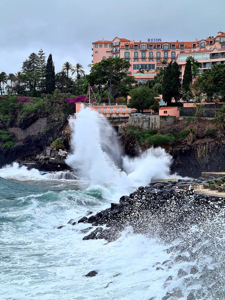 Captivating view of ocean waves crashing against rocky coastline in Funchal, Madeira.
