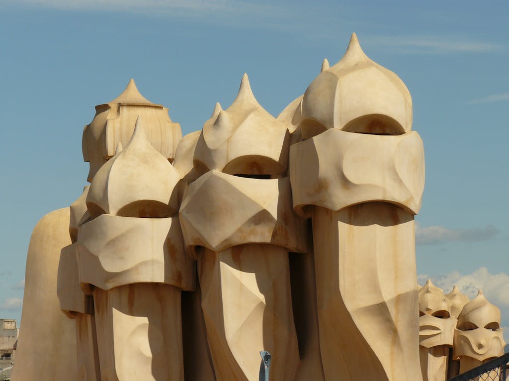 Artistic chimneys of Casa Milà by Gaudí in Barcelona set against a clear sky.