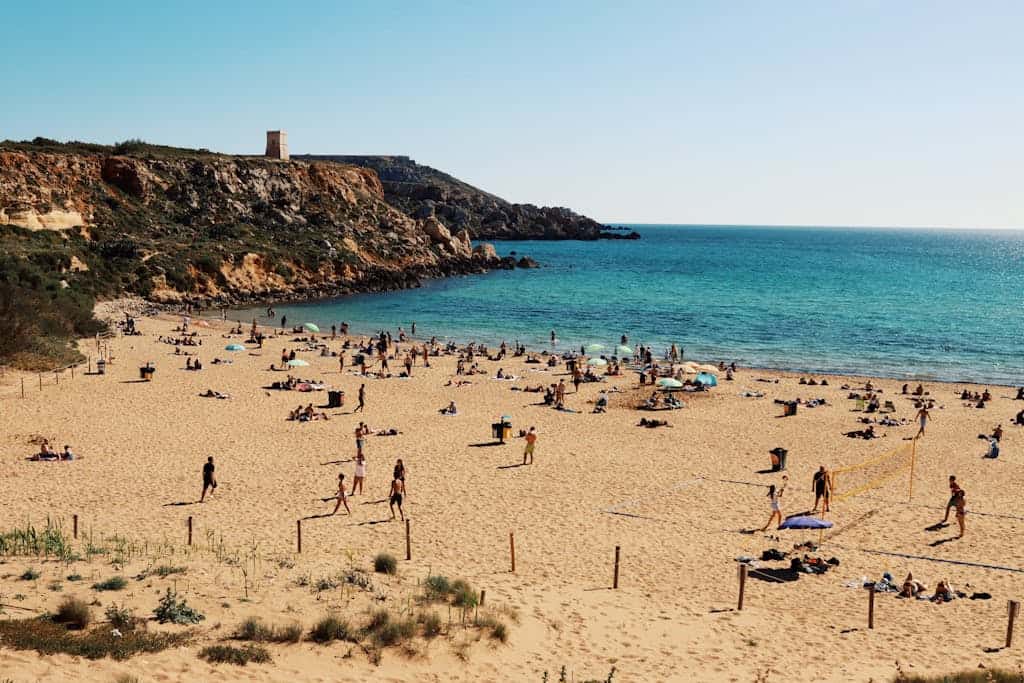 Enjoy a summer day at Golden Bay, Malta, with vibrant beachgoers and scenic cliffs.