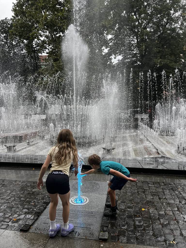 Two children enjoying playing with the magic fountains in central Kosice