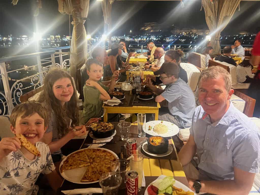 Family eating dinner including pizza, pasta and Egyptian specialities at Nefertiti Hotel rooftop restaurant.