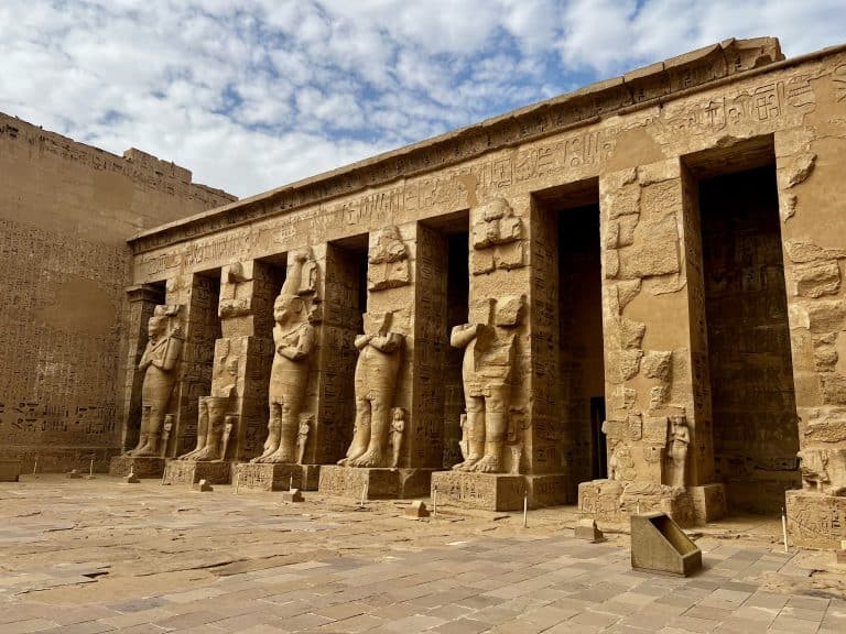 View of the interior of Habu Temple on the West Bank of Luxor, showing carved statues in front of columns.