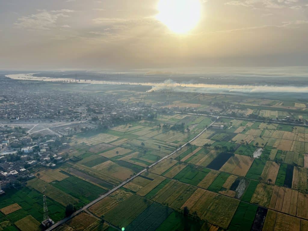 View from the hot air balloon of green fields and early morning mist over the river Nile.