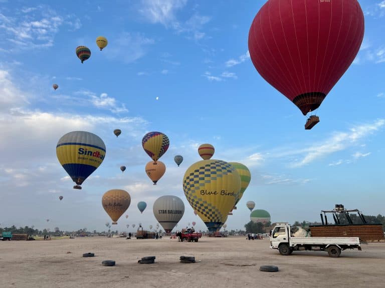 Multiple hot air balloons taking off from an airfield in Luxor, Egypt.