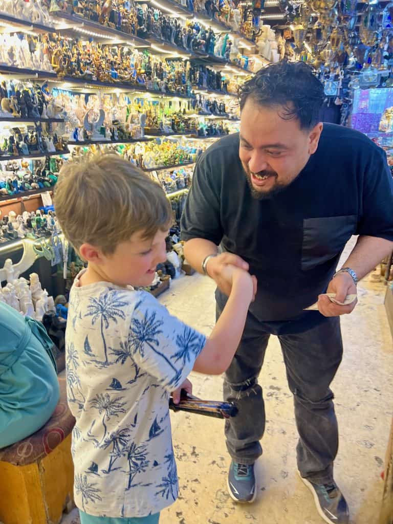 A child shaking hands with a local trader in a shop in the souk of Luxor, Egypt.