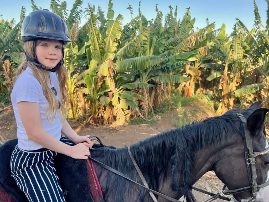 A girl sitting on horseback in Luxor, Egypt, with banana trees visible in the background.