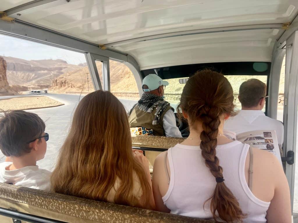 Family seated in an electric tram being driven up the road towards valley of the kings in Luxor, Egypt.