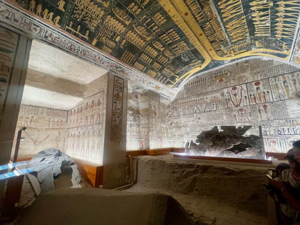 View inside the burial chamber of Ramases V/ VI in valley of the kings Luxor. To the right are the remains of the Saphogaus, with a stone platform containing the remains of a stone coffin to the right. The walls and ceiling are covered in ancient egyptian inscriptions and decoration.
