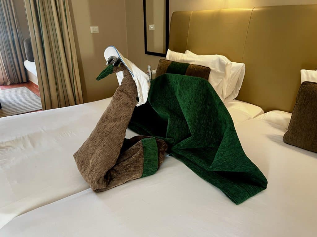 Bedding made into a swan shape by hotel staff at Jaz Makadina hotel, placed on the bed of a family bedroom.