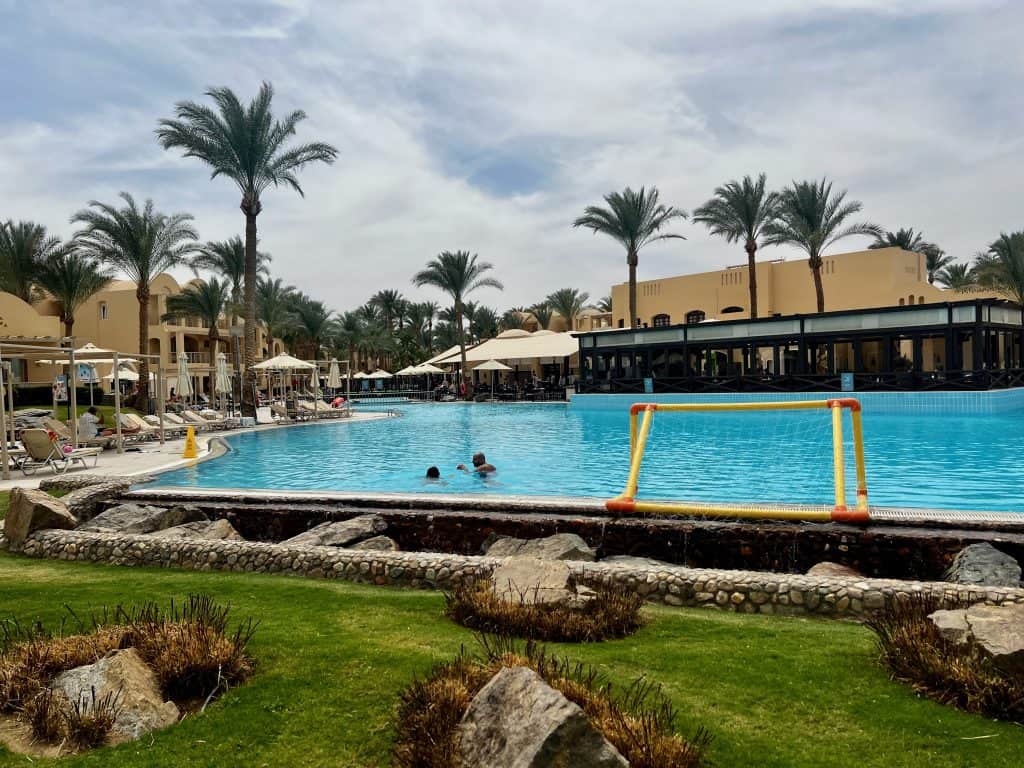 Makadi bay hotel review of Jaz Makadina. Showing the hotel pool with the restaurant and room buildings in the background.