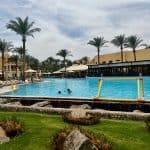 Makadi bay hotel review of Jaz Makadina. Showing the hotel pool with the restaurant and room buildings in the background.