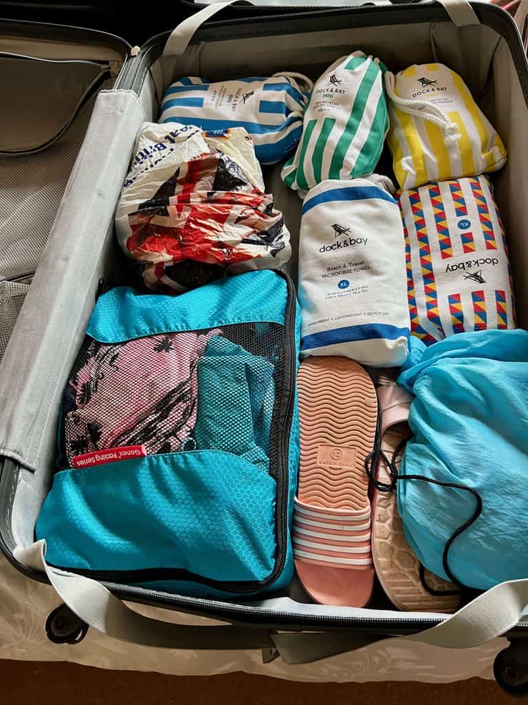 An open suitcase with packing cubes, sliders and dock and bay towels inside.